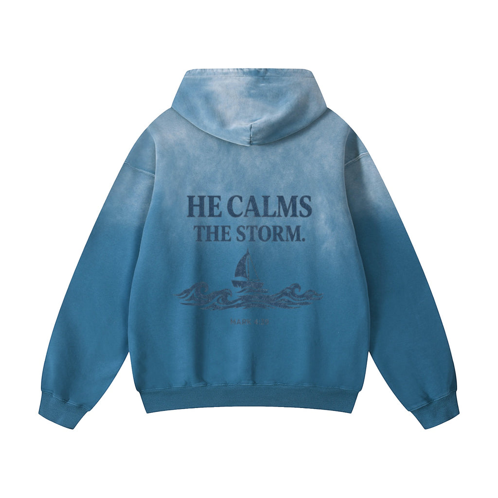 Foundation oversized blue tie-dye hoodie with "HE CALMS THE STORM" graphic and sailboat on back.