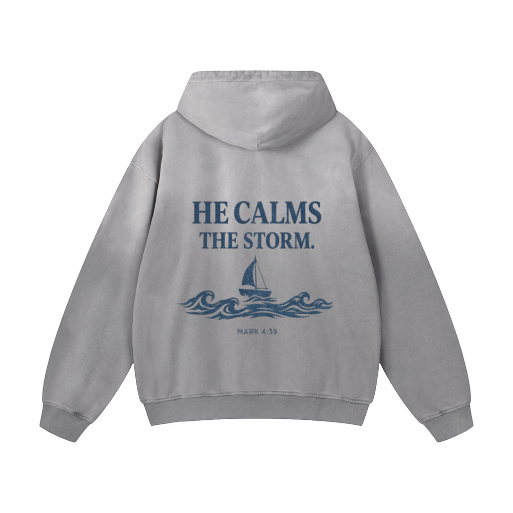 Foundation grey oversized fleece hoodie with "HE CALMS THE STORM. MARK 4:39" graphic and sailboat on waves.
